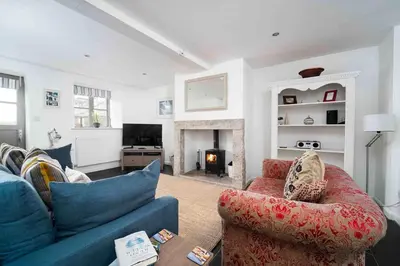 a living room with a blue couch and a fireplace at Quick's Cottage in St Ives