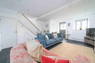 a living room with a blue couch and a tv at Quick's Cottage in St Ives