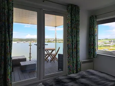 a bedroom with a sliding glass door with a view of the water at 2-bed flat with balcony in Wadebridge