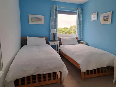 two beds in a room with blue walls and a window at 2-bed flat with balcony in Wadebridge
