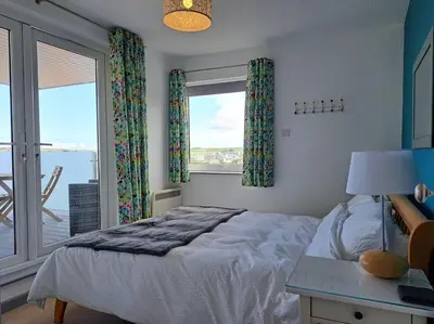 a bedroom with a bed and a large window at 2-bed flat with balcony in Wadebridge