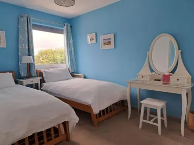 a blue room with two beds and a mirror at 2-bed flat with balcony in Wadebridge