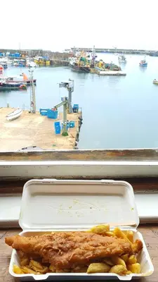 a styrofoam container with fish and vegetables on a table at Harbour Tavern Penthouse in Mevagissey