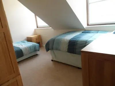 a attic bedroom with two beds and a window at Harbour Tavern Penthouse in Mevagissey