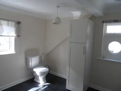 a white bathroom with a toilet and a window at Harbour Tavern Penthouse in Mevagissey