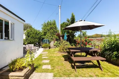 a picnic table and an umbrella in a garden at Good Life on the Coast in Falmouth