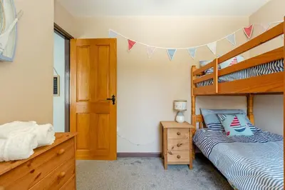 a bedroom with two bunk beds and a wooden cabinet at Good Life on the Coast in Falmouth