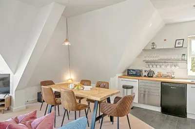a kitchen and dining room with a wooden table and chairs at Pentire Point - Coastal Penthouse, Beaches, River & Restaurants All Within Short Walk in Newquay