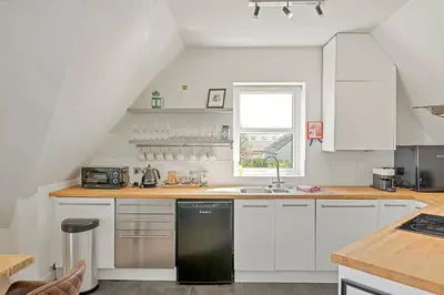 a kitchen with white cabinets and a black dishwasher at Pentire Point - Coastal Penthouse, Beaches, River & Restaurants All Within Short Walk in Newquay