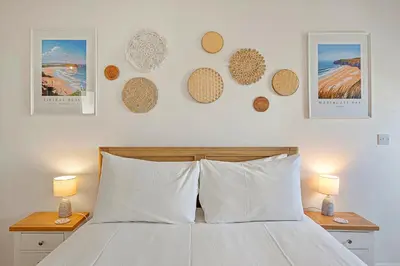 a bedroom with a bed with two night stands and two lamps at Pentire Point - Coastal Penthouse, Beaches, River & Restaurants All Within Short Walk in Newquay