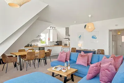 a living room with a blue couch and a table at Pentire Point - Coastal Penthouse, Beaches, River & Restaurants All Within Short Walk in Newquay