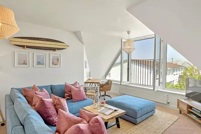 a living room with a blue couch and a table at Pentire Point - Coastal Penthouse, Beaches, River & Restaurants All Within Short Walk in Newquay
