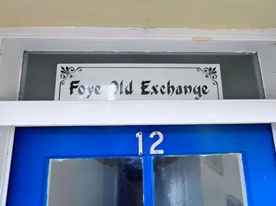 a sign above a blue door with the words love all exchange at Historic Fowey Home by the Quay in Fowey