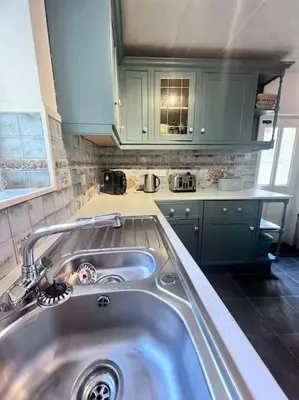 a kitchen with a sink and green cabinets at Historic Fowey Home by the Quay in Fowey