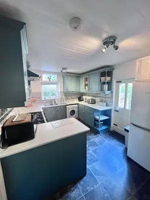 a kitchen with blue cabinets and a white refrigerator at Historic Fowey Home by the Quay in Fowey