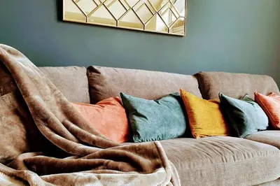a brown couch with colorful pillows on it at 6 Porth Sands Newquay Cornwall Luxury with Sea Views in Newquay