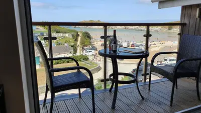 a balcony with a table and chairs and a view of a beach at 6 Porth Sands Newquay Cornwall Luxury with Sea Views in Newquay