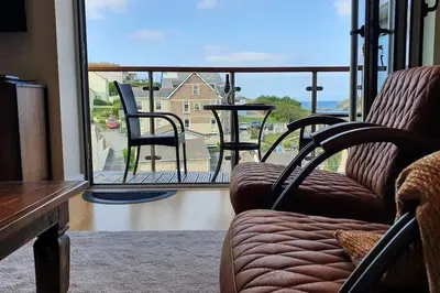 a living room with chairs and a view of a balcony at 6 Porth Sands Newquay Cornwall Luxury with Sea Views in Newquay