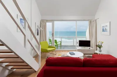 a living room with a red couch and a view of the ocean at 24 Piazza in St Ives