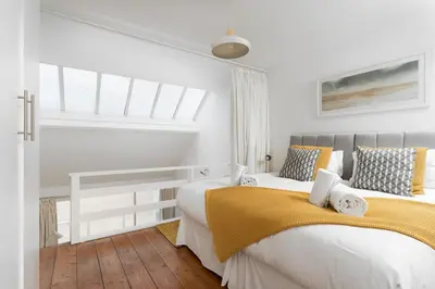 two beds in a bedroom with white walls and wood floors at 24 Piazza in St Ives