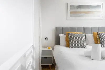 a bedroom with a bed with white and yellow pillows at 24 Piazza in St Ives