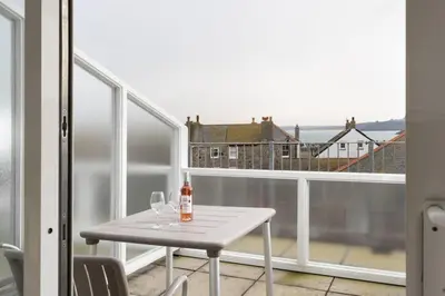 a table with wine glasses and a bottle on a balcony at 24 Piazza in St Ives