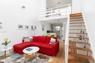 a red couch in a living room with a staircase at 24 Piazza in St Ives