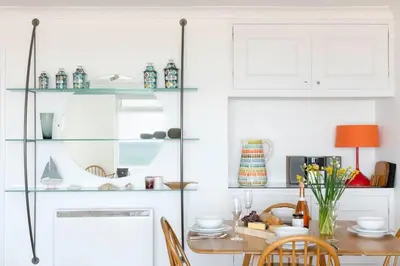 a dining room with a table and a glass shelf at 11 Barnaloft in St Ives
