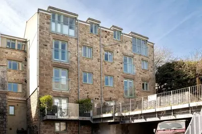 a large brick building with a bridge in front of it at 8 Sunday School Court in St Ives