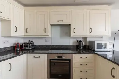 a kitchen with white cabinets and a black counter top at 8 Sunday School Court in St Ives