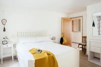 a bedroom with a white bed with a yellow blanket on it at Bodeeve in Penzance