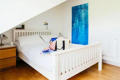 a bedroom with a white bed and a blue curtain at Bodeeve in Penzance