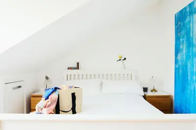 a bedroom with a white bed with a bag on it at Bodeeve in Penzance