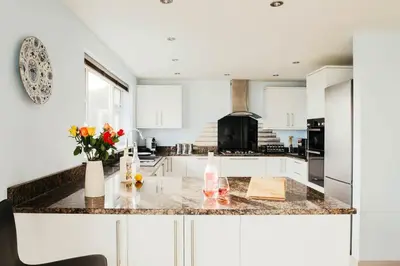 a kitchen with white cabinets and a marble counter top at Bodeeve in Penzance