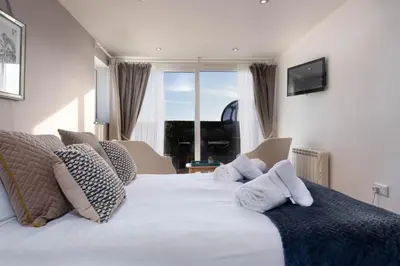 a bedroom with a large white bed with a window at The Cove in Praa Sands