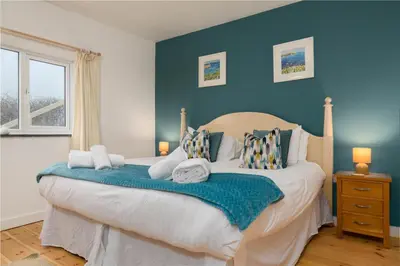 a bedroom with a large bed with blue walls at The Cove in Praa Sands