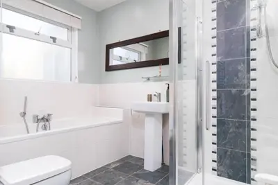 a white bathroom with a sink and a shower at The Cove in Praa Sands