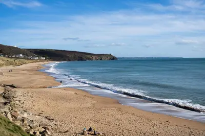 a beach with people on the sand and the ocean at The Cove in Praa Sands