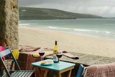 a table with two glasses of wine on the beach at 6 Barnaloft in St Ives