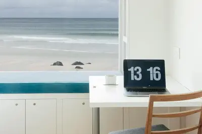 a desk with a laptop sitting on top of it next to a beach at 6 Barnaloft in St Ives