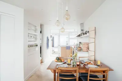 a white kitchen with a wooden table and chairs at 6 Barnaloft in St Ives