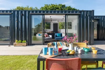 a patio with a table and chairs and a house at Trevassack Holidays in Helston
