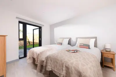 two beds in a white room with a window at Trevassack Holidays in Helston