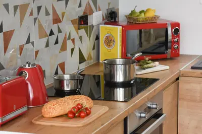 a kitchen counter with a red microwave and a cutting board at Trevassack Holidays in Helston