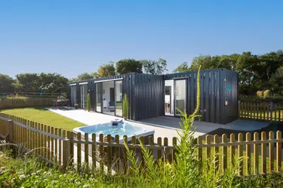 a tiny house with a hot tub in a yard at Trevassack Holidays in Helston
