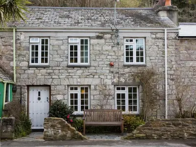 a stone house with a bench in front of it at Holiday Home The Old Inn by Interhome in Pentewan