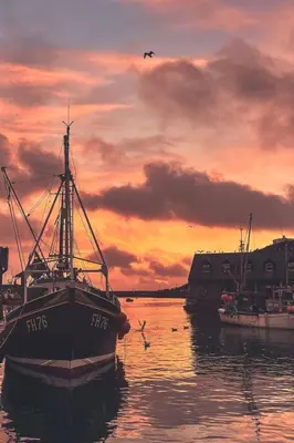 a boat sitting in the water at sunset at Holiday Home The Old Inn by Interhome in Pentewan