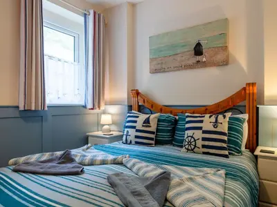 a bedroom with a bed with a bird on the wall at Apartment Jetty Cottage by Interhome in Mevagissey