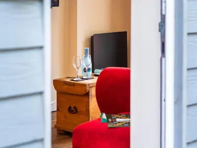 a room with a red chair and a bottle of wine at Apartment Jetty Cottage by Interhome in Mevagissey