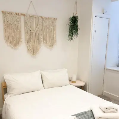 a bedroom with a bed with white sheets and a plant on the wall at Ground Floor Couples Retreat in Newquay